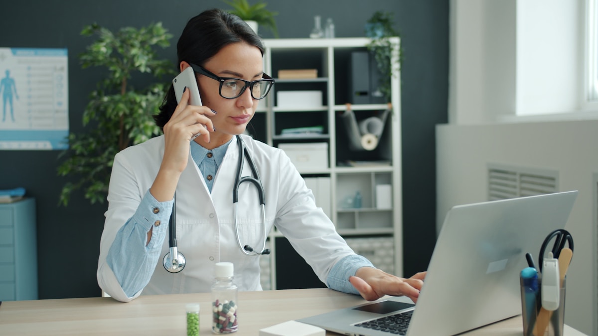 Doctor checking phone for incoming patient transfer